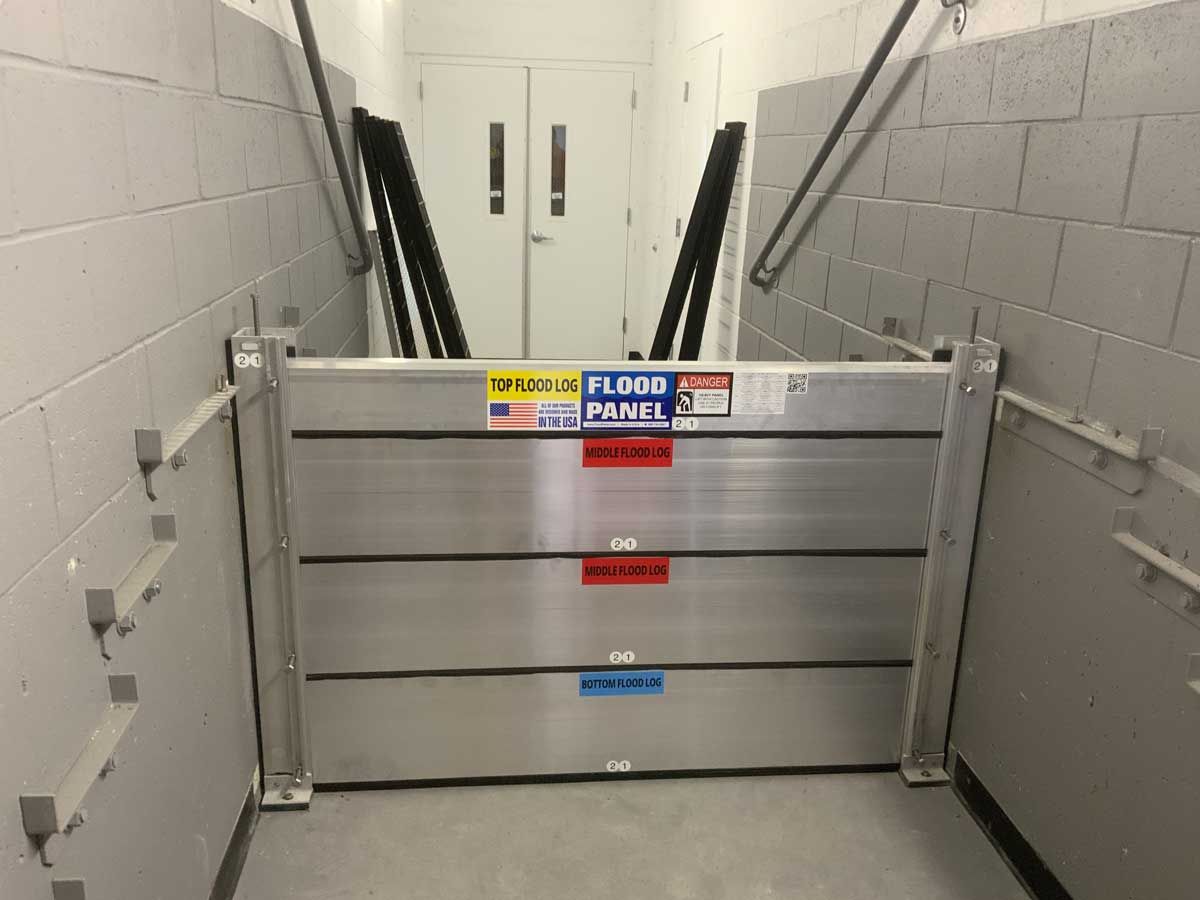 A flood barrier is in a hallway next to a staircase.