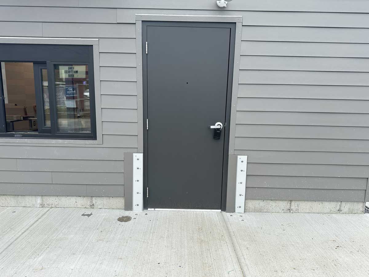 A gray building with a black door and a window