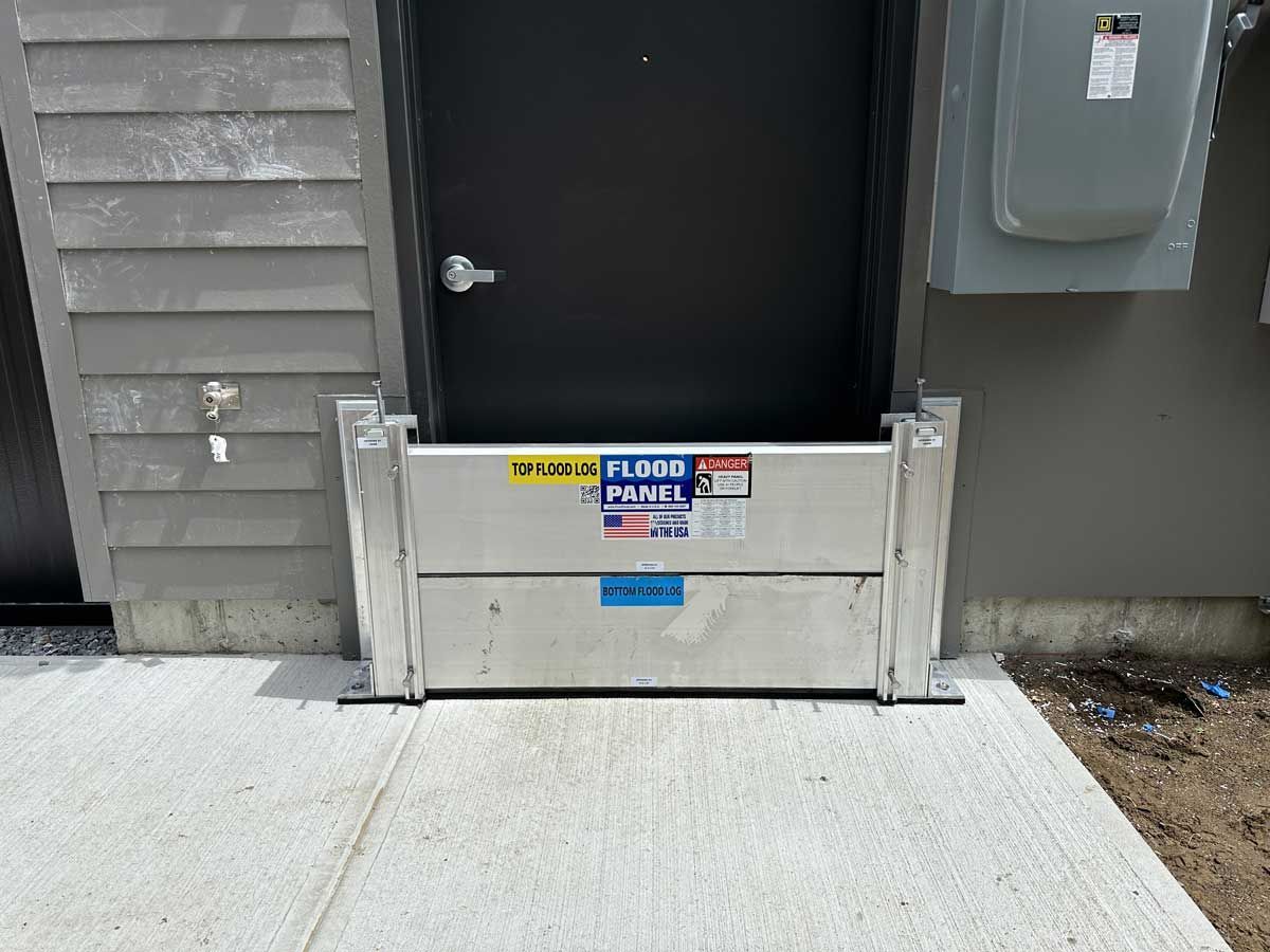 A flood barrier is sitting on the sidewalk in front of a door.