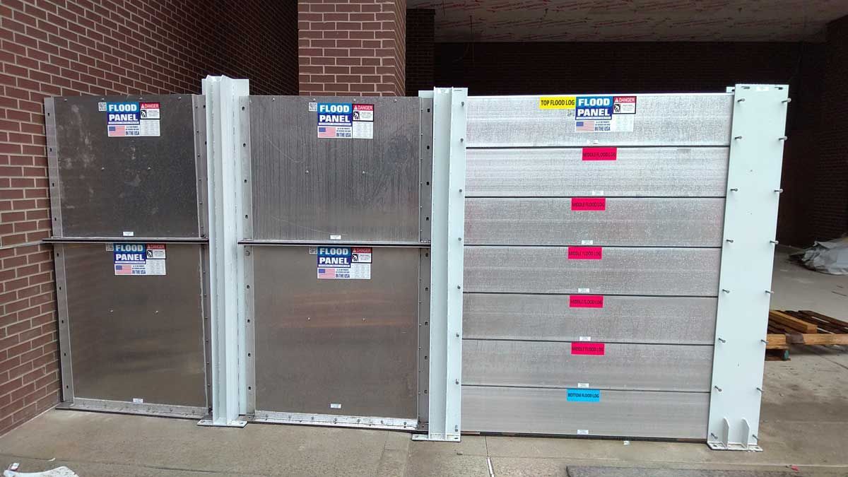 A row of aluminum flood barriers in front of a brick building
