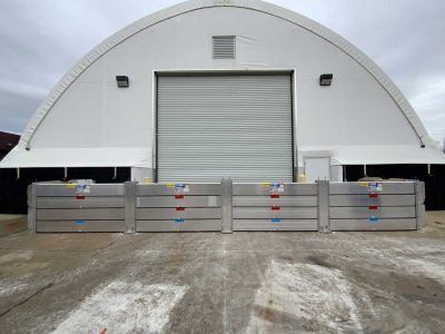 A large white building with a garage door and a flood barrier in front of it.
