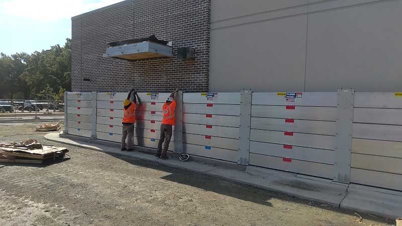 Two construction workers are working on a fence in front of a building.
