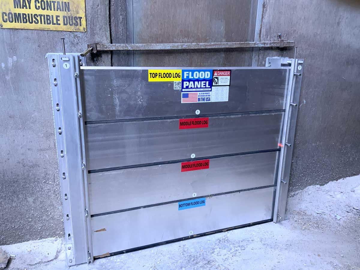 A stainless steel flood barrier is sitting on the side of a building.