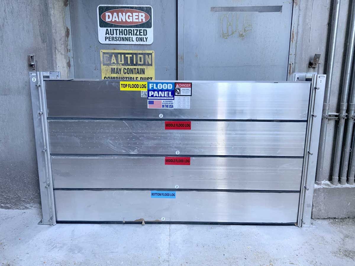 A flood barrier is sitting in front of a building with a danger sign on it.