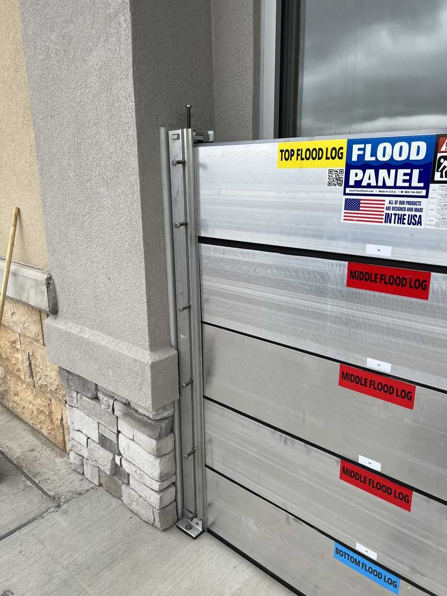 A flood panel is sitting on the sidewalk next to a building.