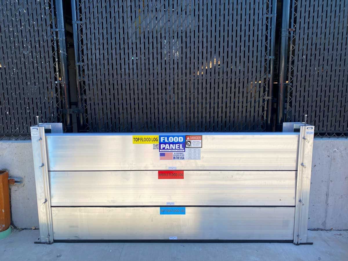 A metal barrier is sitting in front of a fence.