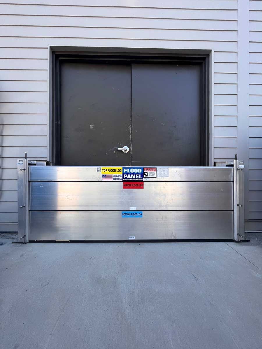 A stainless steel flood barrier is in front of a door
