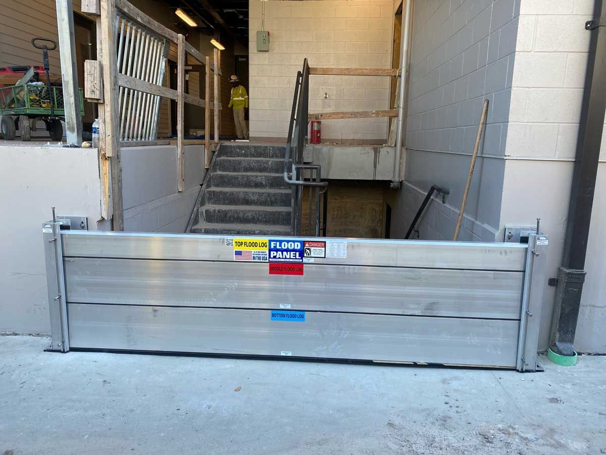 A flood barrier is sitting in front of a building next to stairs.
