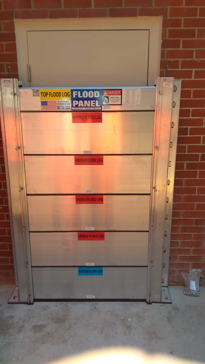 A flood barrier is sitting in front of a brick wall.