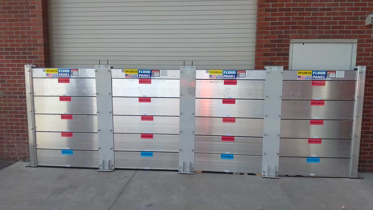 A row of aluminum barriers are lined up in front of a brick building