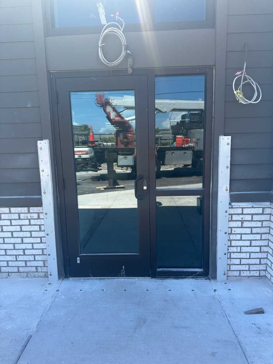 A building under construction with a reflection of a truck in the glass doors.