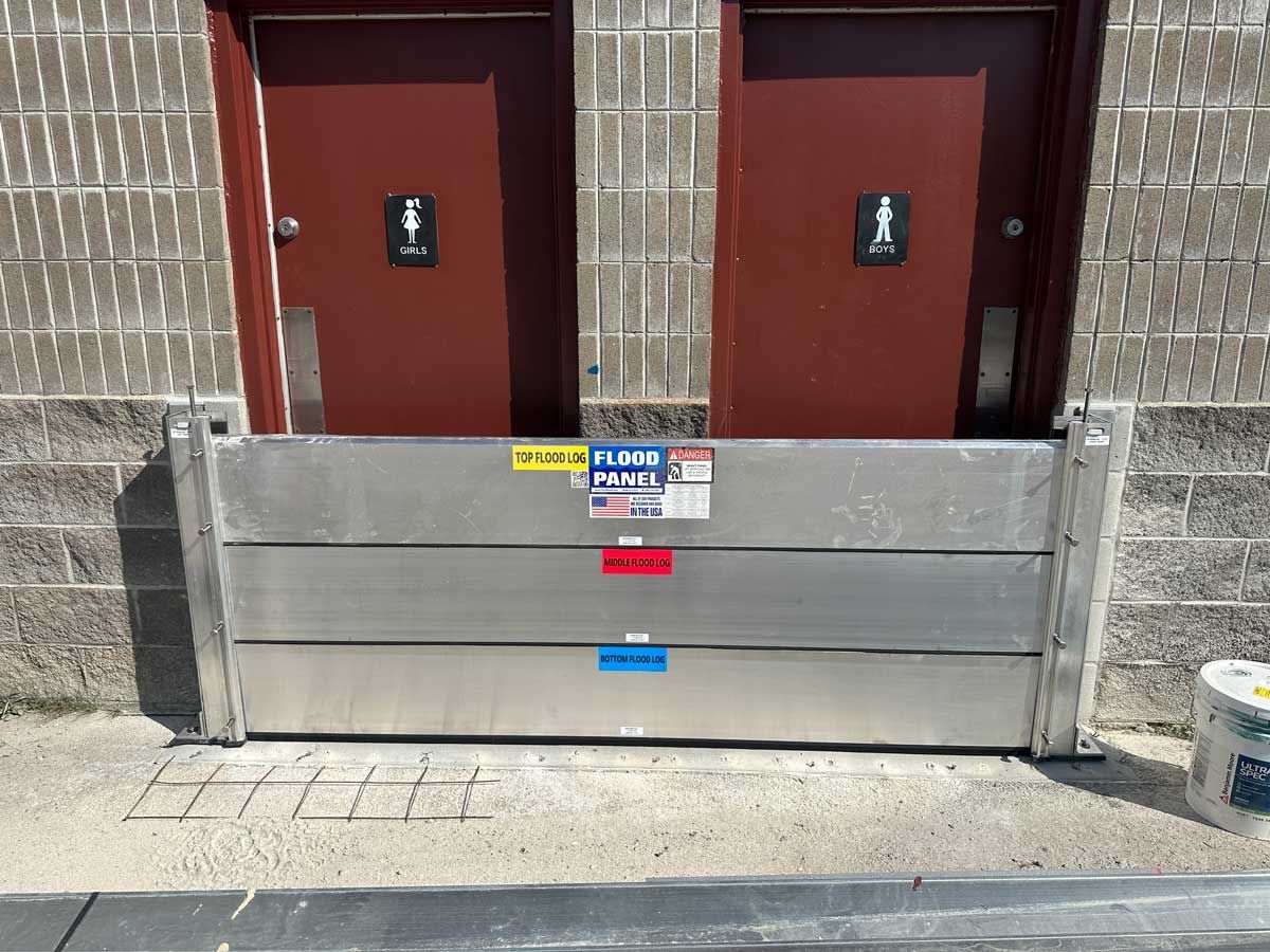 A flood barrier is sitting in front of a building with two doors.