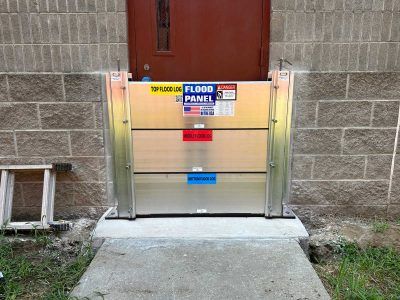 A flood panel is sitting on the sidewalk in front of a brick building.
