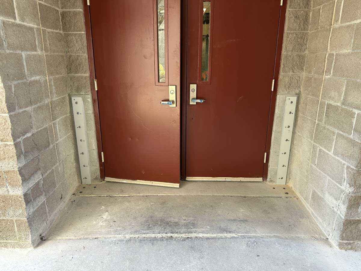 A pair of red doors are sitting next to each other on a brick wall.