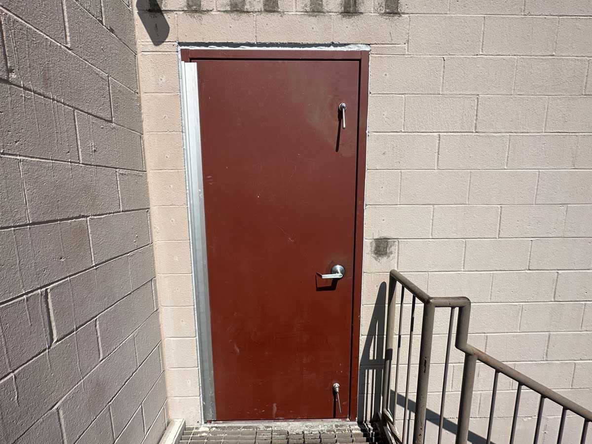 A brown door is on a brick wall next to a staircase.