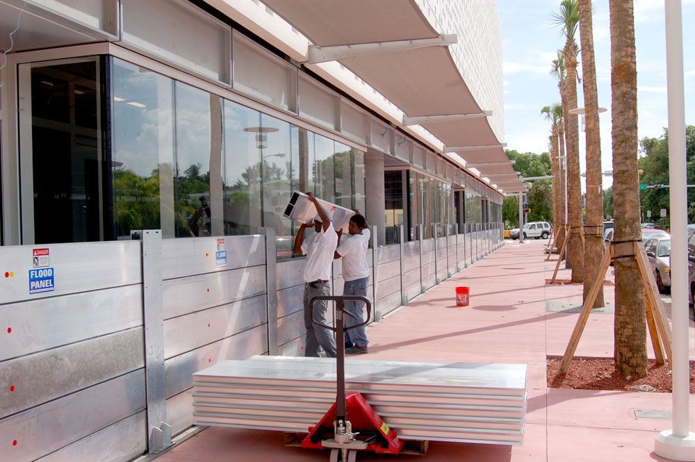 A man is carrying a stack of aluminum sheets on a cart