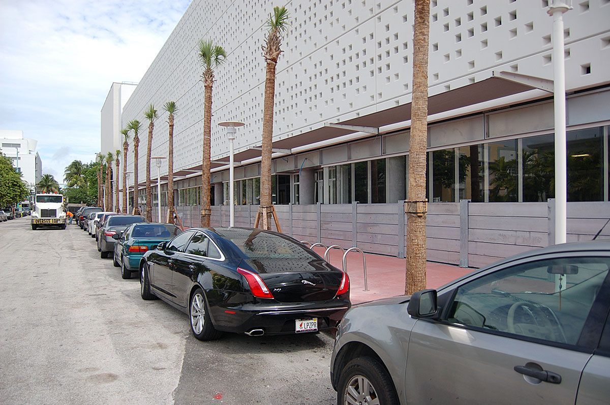 A row of cars are parked in front of a building