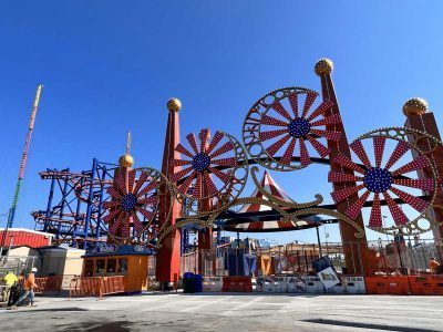 A large ferris wheel is in the middle of an amusement park.