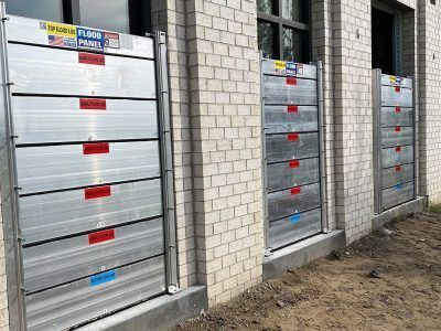 A row of aluminum flood barriers on the side of a brick building.