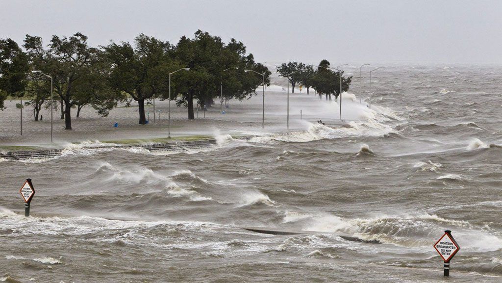 A man is standing in the middle of a flooded area in the ocean