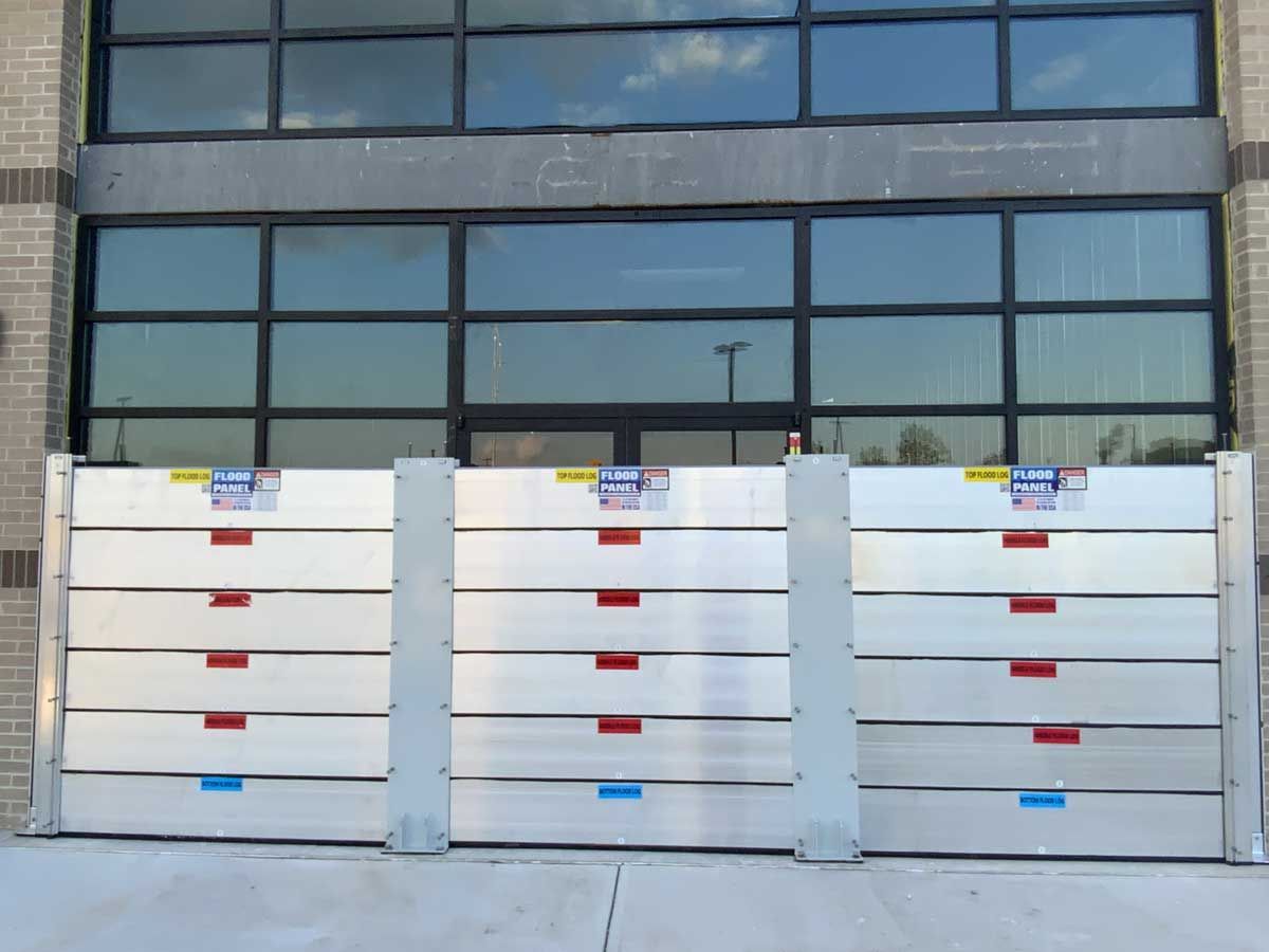 A row of aluminum flood barriers in front of a building.