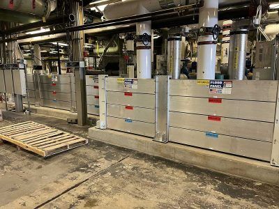 A warehouse with a lot of pipes and a wooden pallet on the floor.