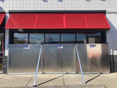 A building with a red awning and a stainless steel fence in front of it.