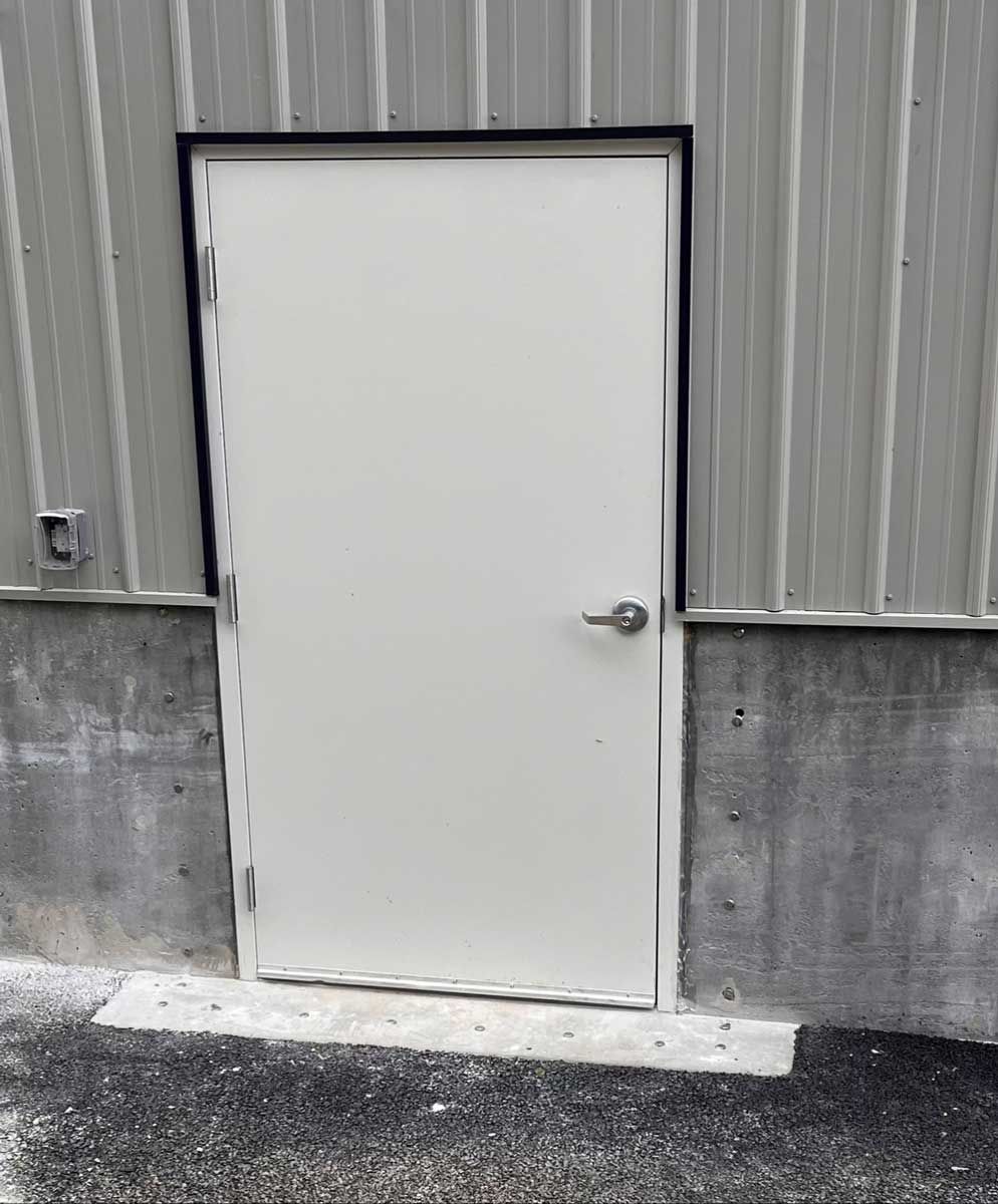A white door is sitting on the side of a building.