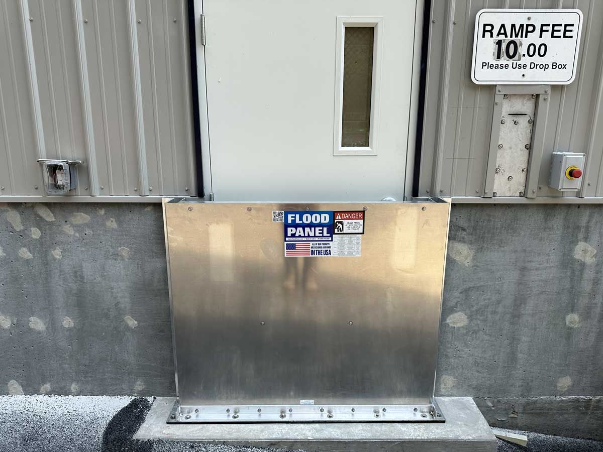 A stainless steel flood panel is attached to the side of a building.