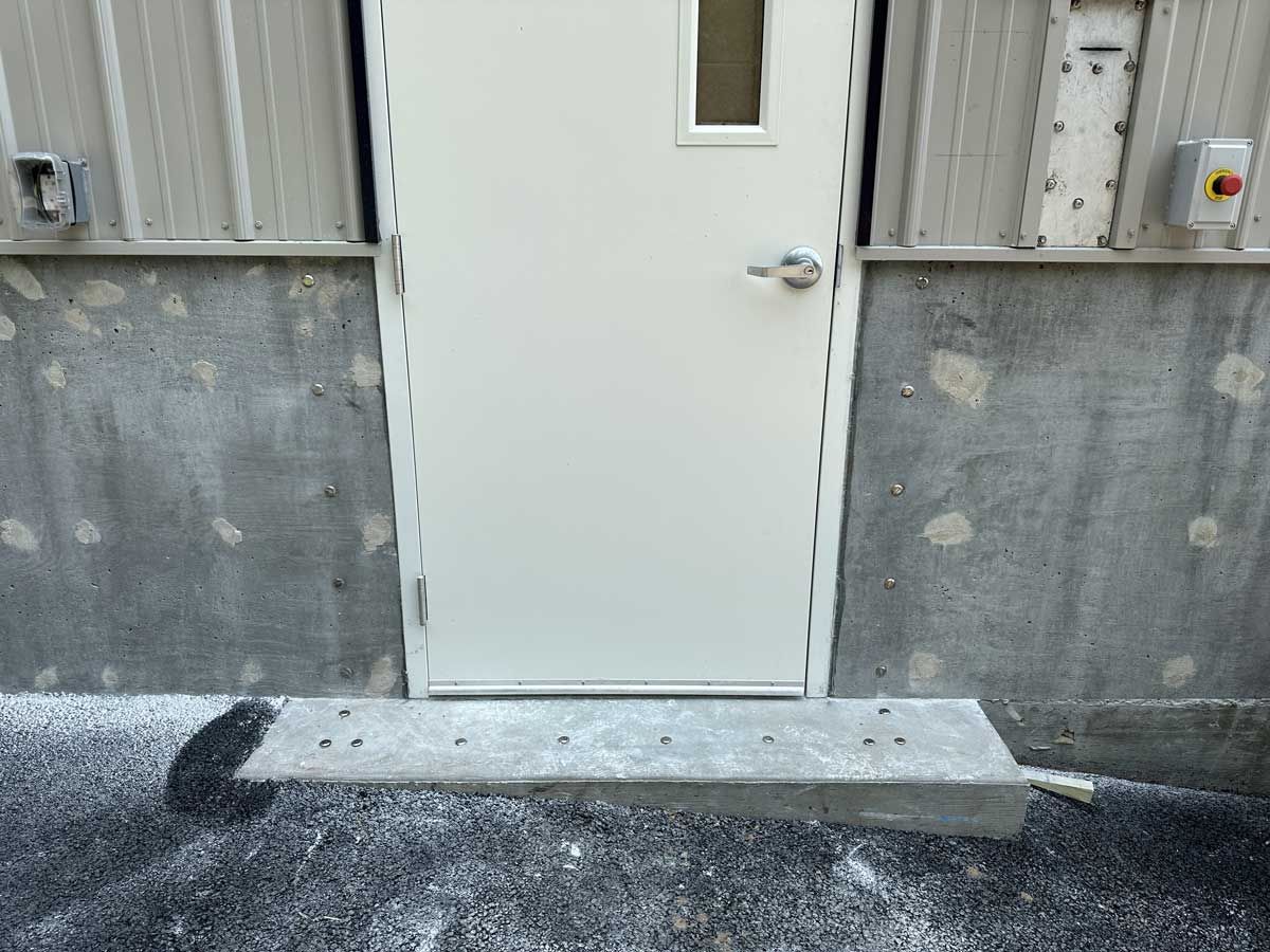 A white door is sitting next to a concrete wall.