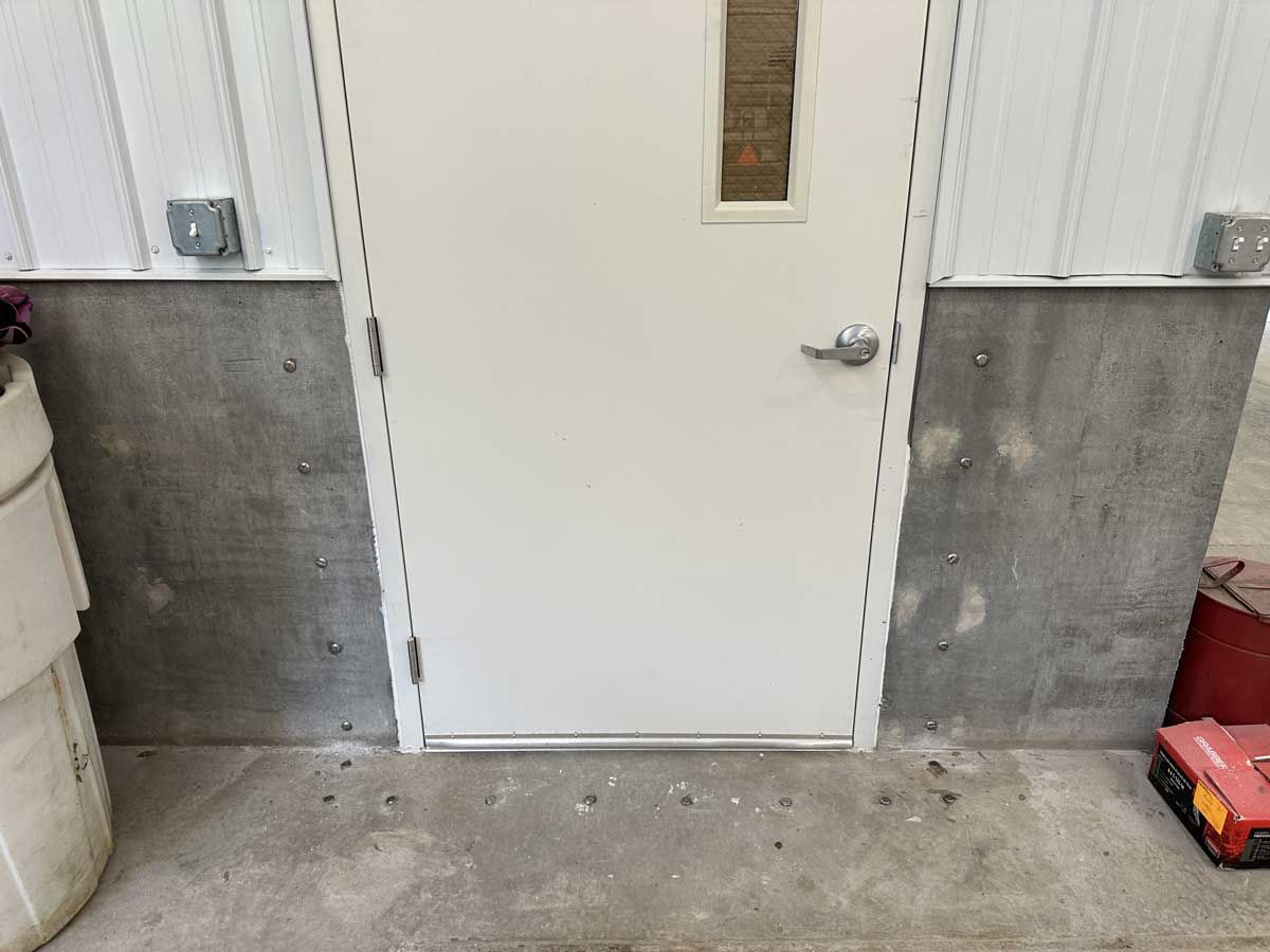 A white door is sitting next to a concrete wall.