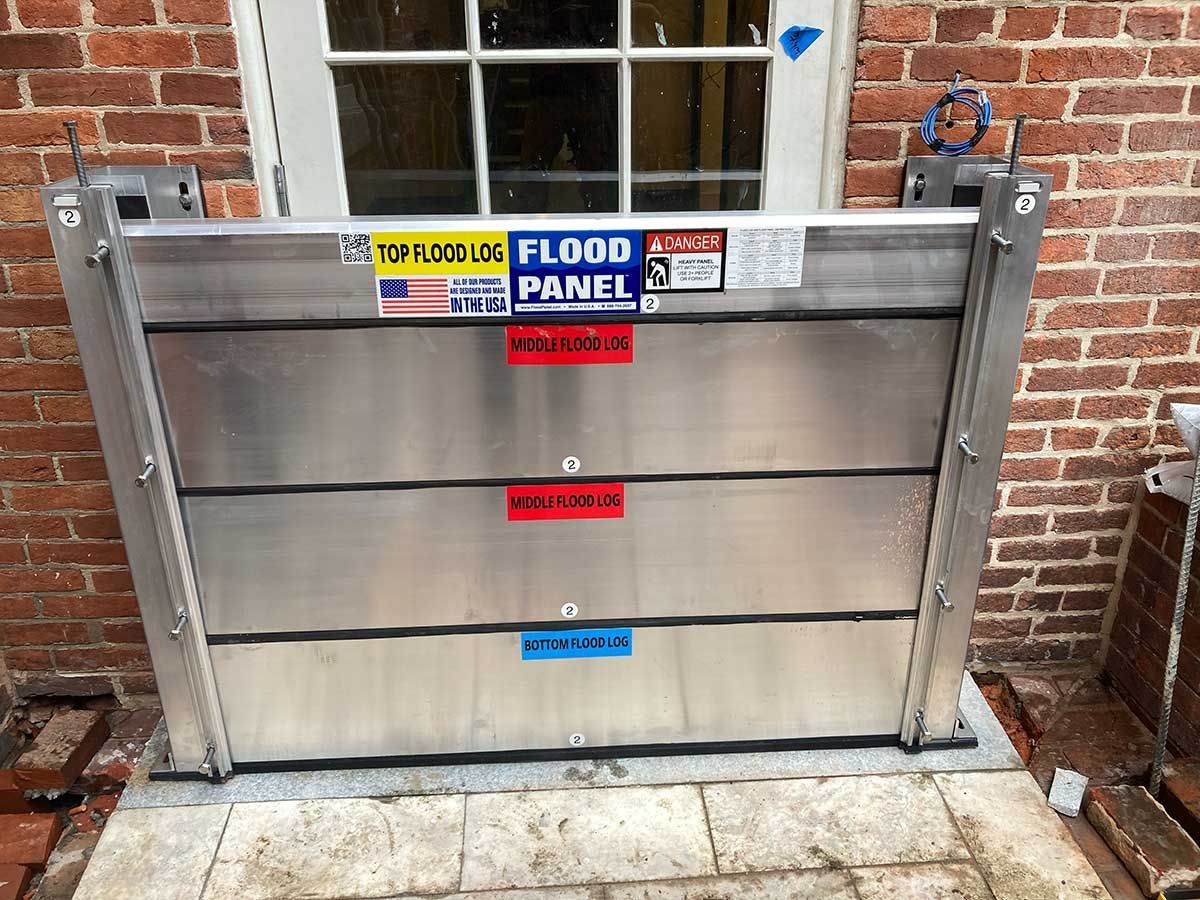 A flood panel is sitting in front of a brick building.