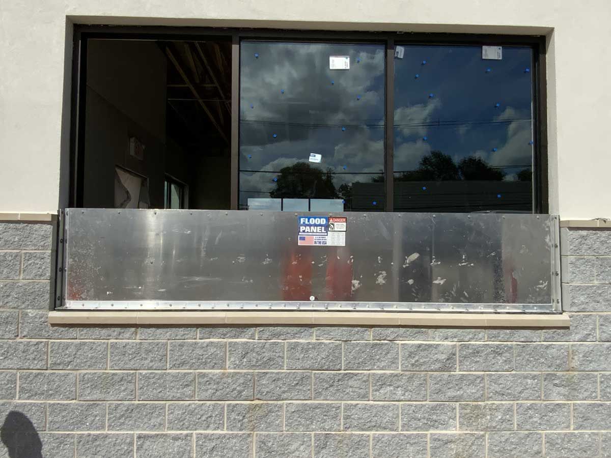 A large window with a stainless steel railing on a brick wall.