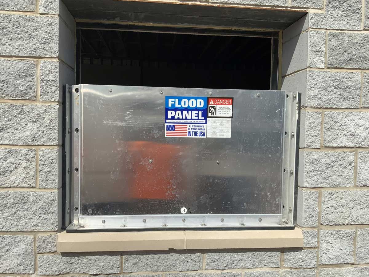A flood panel is attached to a window on a brick wall