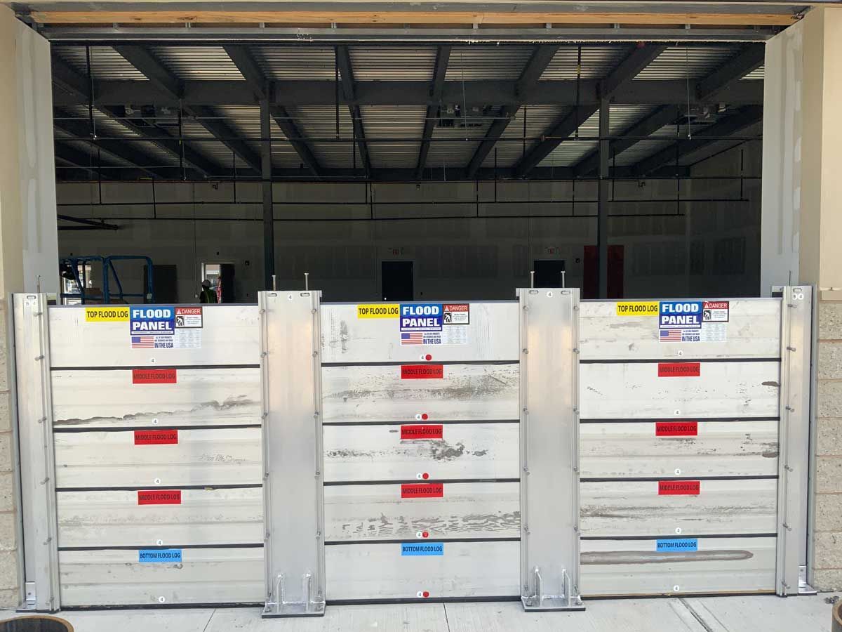 A row of aluminum flood barriers in front of a garage door.
