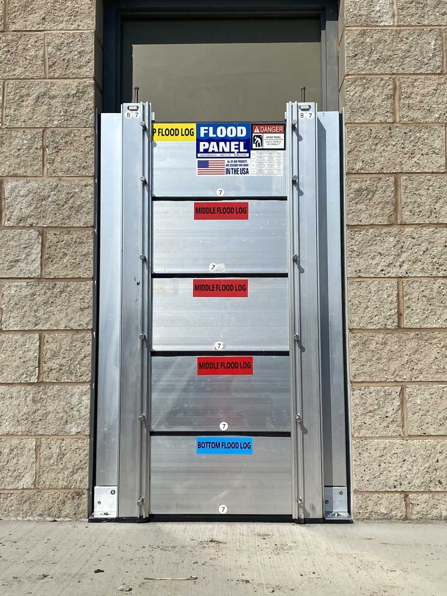 A flood panel is sitting in front of a brick building.