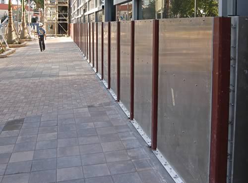 A man walking down a sidewalk next to a fence