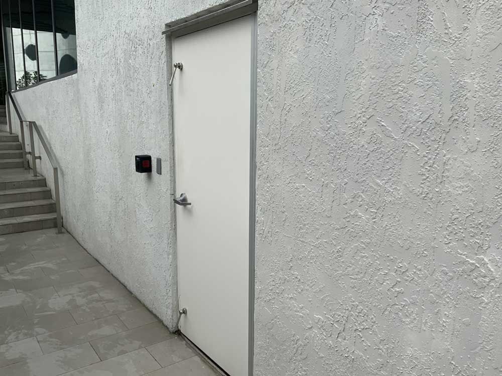 A white door is on a white wall next to stairs.