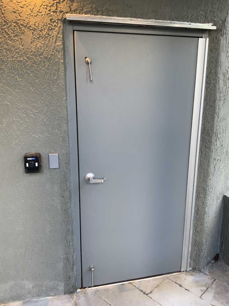 A gray door with a key on it is on a wall.