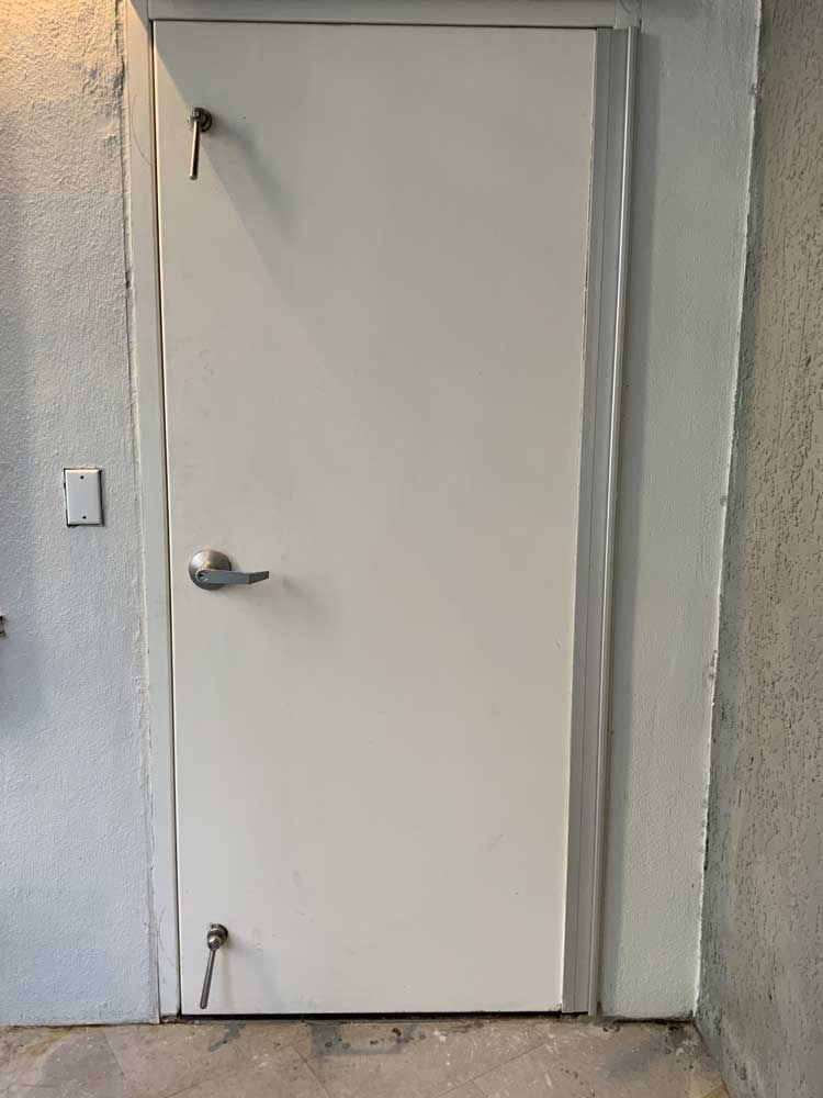 A white door with a silver handle is hanging on a wall.