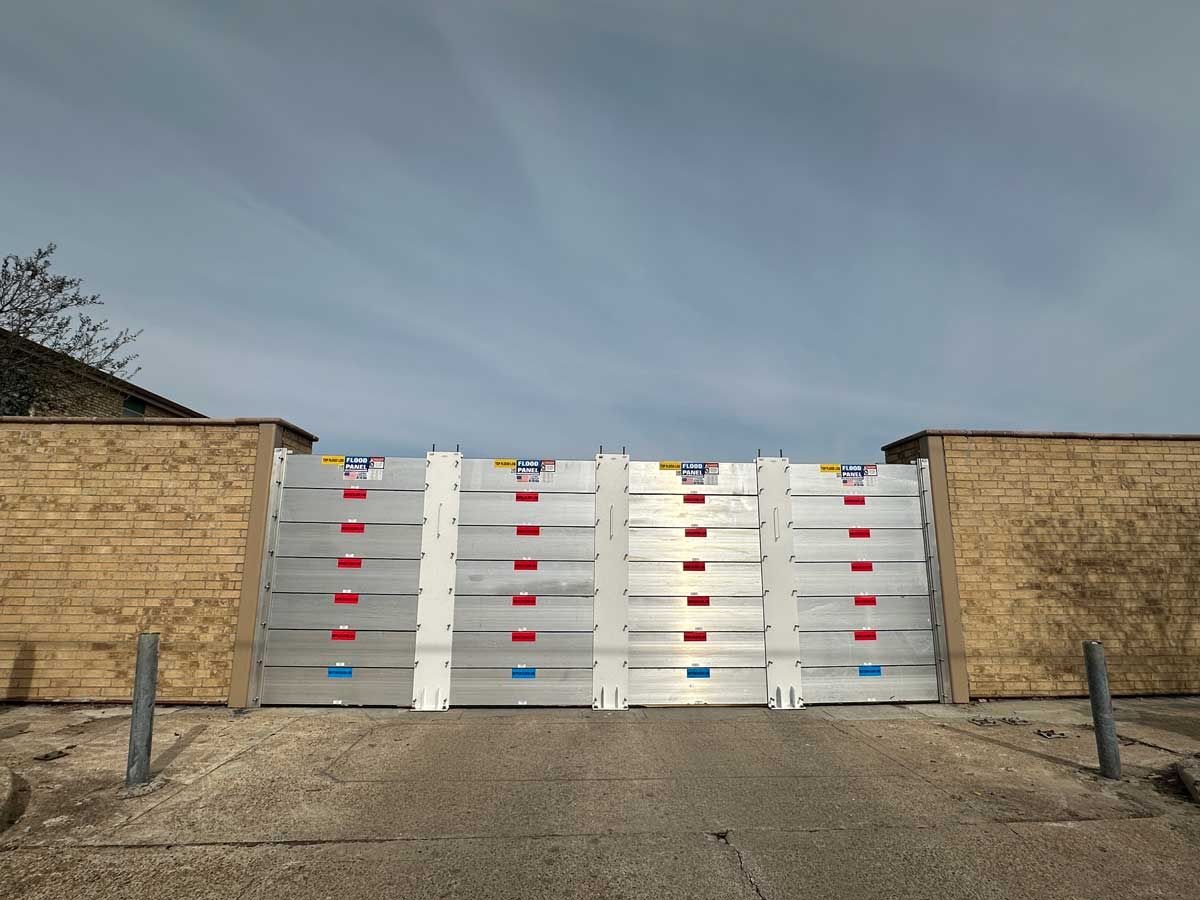 A flood barrier is sitting on the side of a road next to a brick wall.