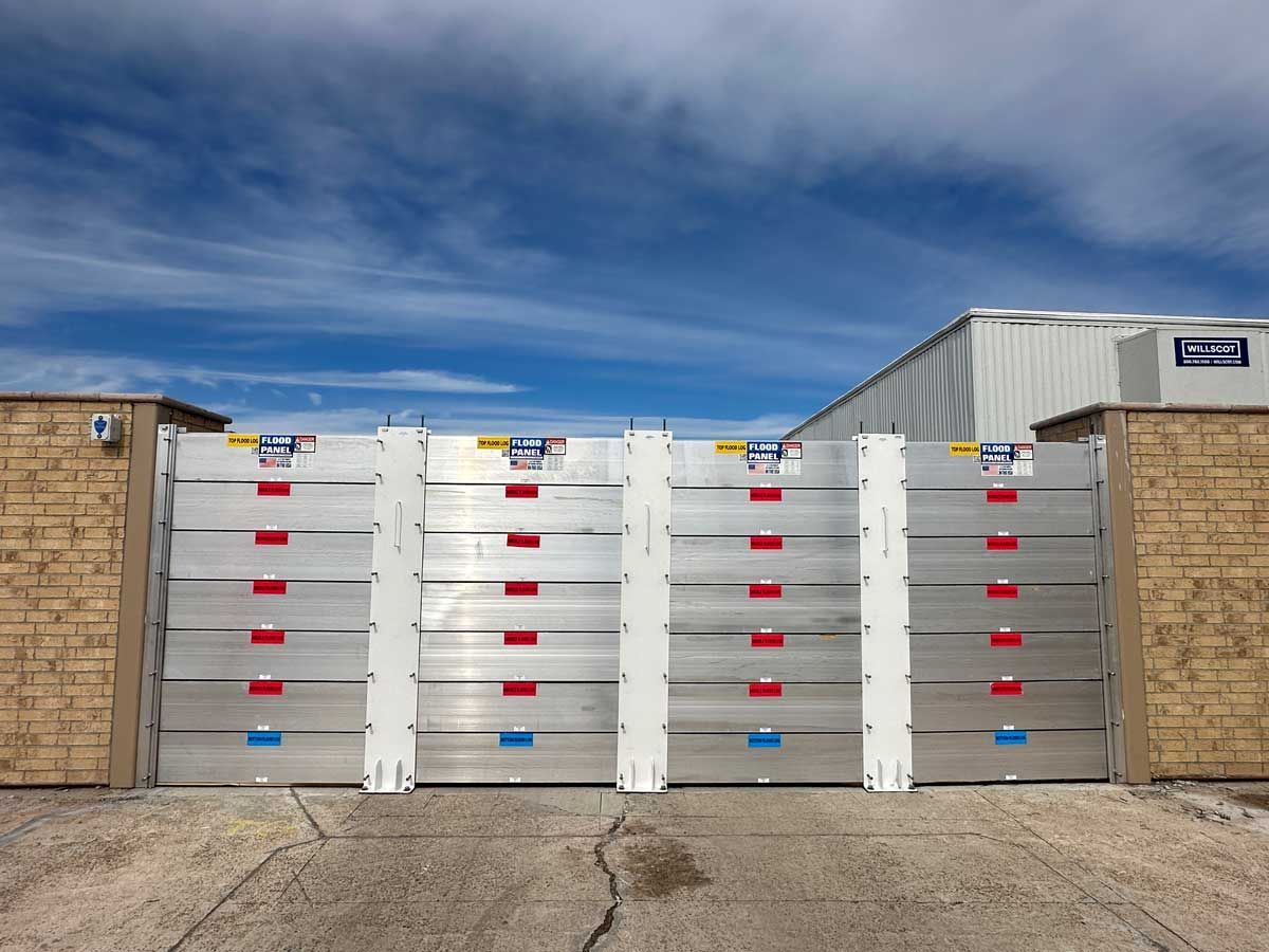 A row of aluminum flood barriers are sitting next to a brick wall.