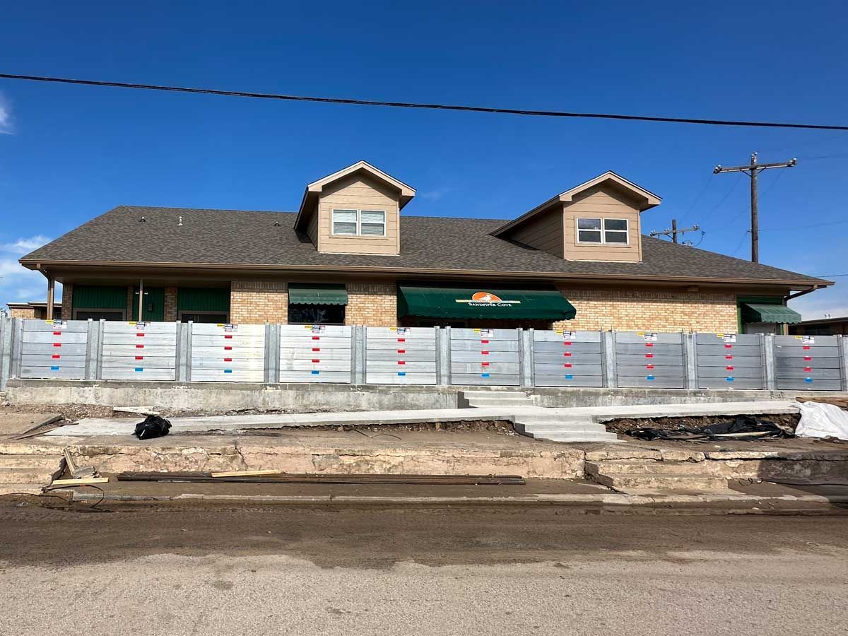 A house with a green awning is behind a metal fence