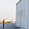 A man is standing in front of a large white building.