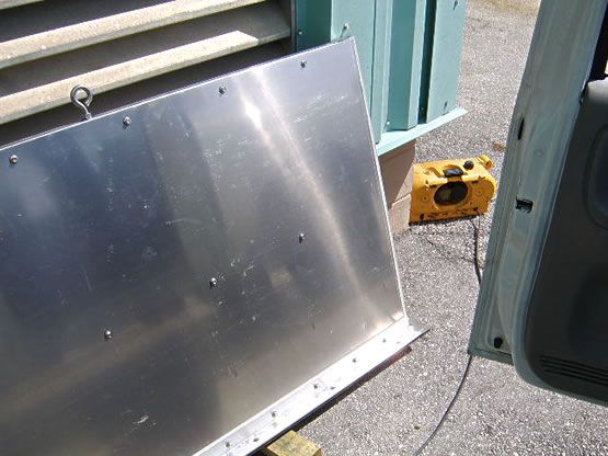 A piece of metal is sitting on the ground next to a yellow box.