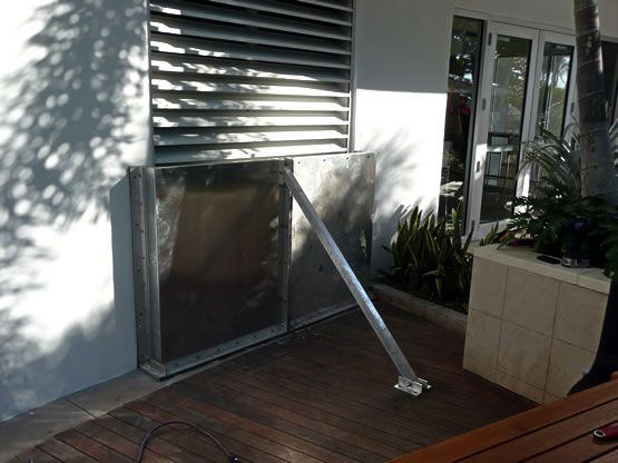 A stainless steel box is sitting on a wooden deck in front of a building.