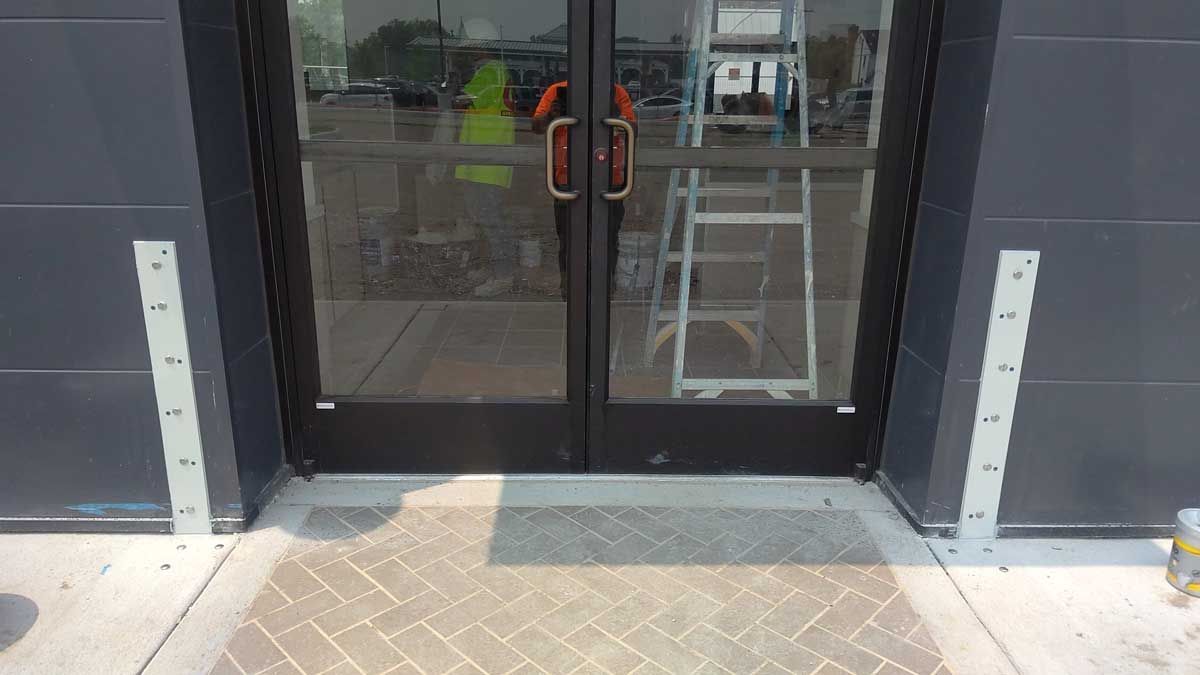 A ladder is sitting on the sidewalk in front of a door.