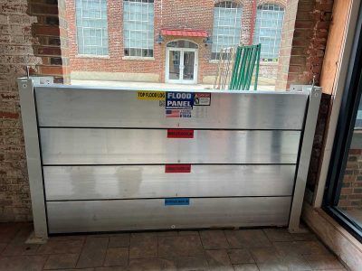 A flood barrier is sitting in front of a brick building.