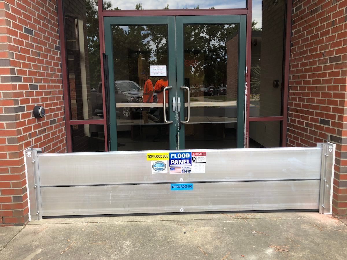 A flood barrier is sitting in front of a brick building.