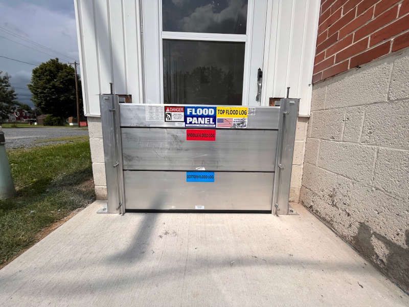 A flood panel is sitting on the sidewalk in front of a door.